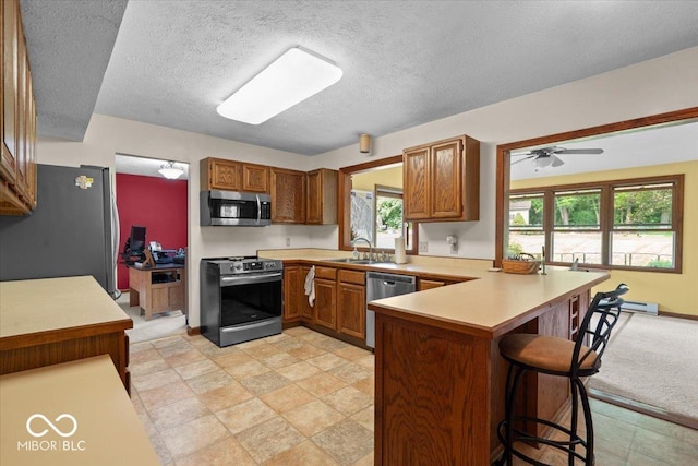 14814 Beacon Blvd, Carmel, IN 46032 - kitchen with stainless steel appliances, a sink, a peninsula, a kitchen breakfast bar, and light countertops
