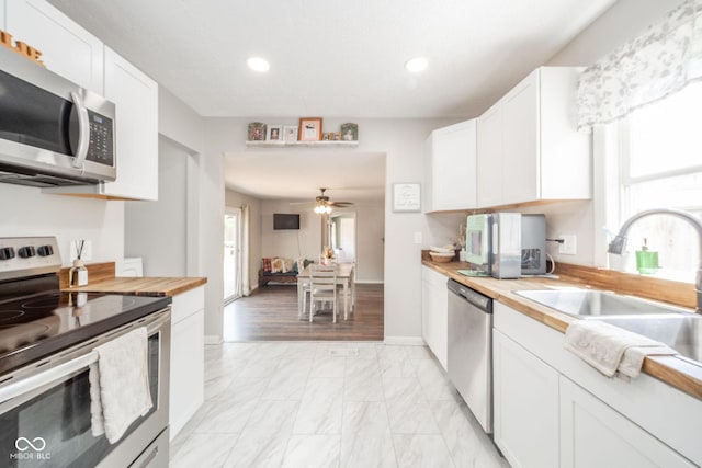 433 N 15th Ave, Beech Grove, IN 46107 - kitchen with appliances with stainless steel finishes, butcher block countertops, light marble finish flooring, a sink, and recessed lighting