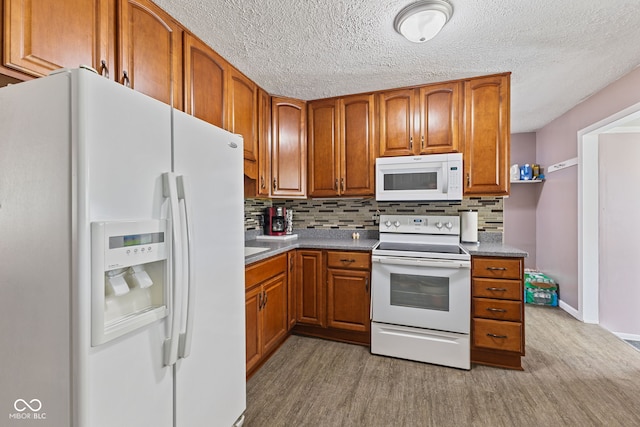 5115 Bertha St, Indianapolis, IN 46241 - kitchen featuring white appliances, brown cabinetry, tasteful backsplash, light wood finished floors, and a textured ceiling