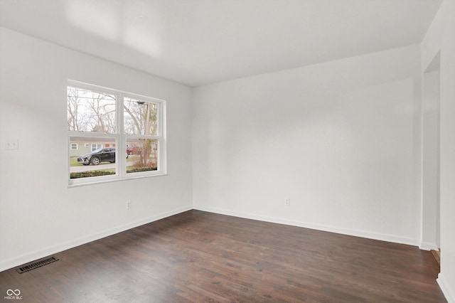 spare room featuring dark wood-style flooring and baseboards