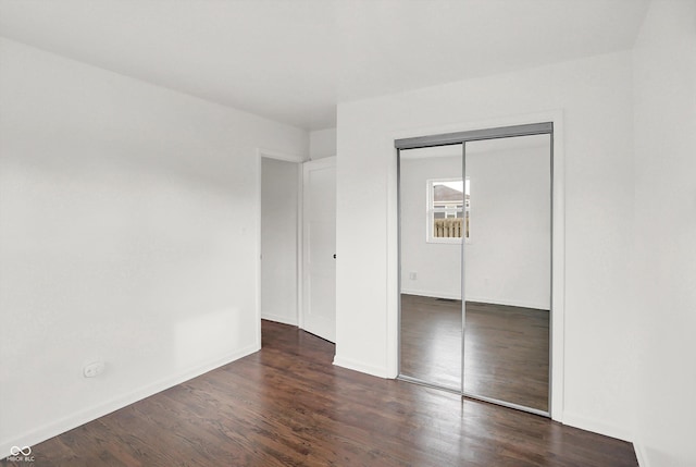unfurnished bedroom featuring wood finished floors, a closet, and baseboards