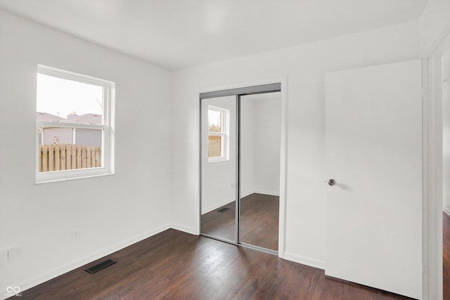 unfurnished bedroom featuring dark wood-style floors, a closet, and baseboards