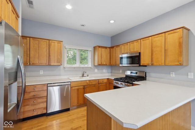 455 S Pine St Unit 4, Indianapolis, IN 46203 - kitchen with stainless steel appliances, a peninsula, a sink, light countertops, and light wood-style floors