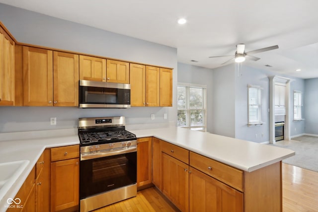 455 S Pine St Unit 4, Indianapolis, IN 46203 - kitchen featuring appliances with stainless steel finishes, a peninsula, a ceiling fan, light countertops, and light wood-style flooring