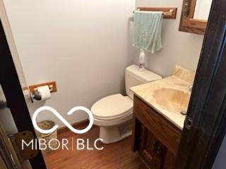 8835 Winding Ridge Rd, Indianapolis, IN 46217 - half bathroom featuring toilet, vanity, and wood finished floors