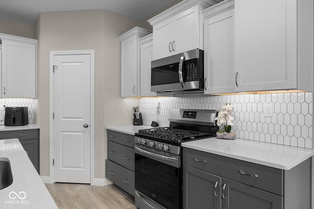3583 Collier Dr, Lafayette, IN 47905 - kitchen with stainless steel appliances, gray cabinetry, light wood-style floors, decorative backsplash, and light stone countertops