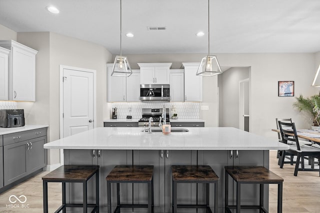 3583 Collier Dr, Lafayette, IN 47905 - kitchen with appliances with stainless steel finishes, a sink, tasteful backsplash, a kitchen breakfast bar, and light wood-style floors