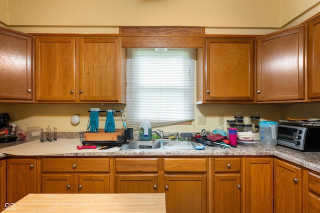 kitchen with a sink, light countertops, and brown cabinets