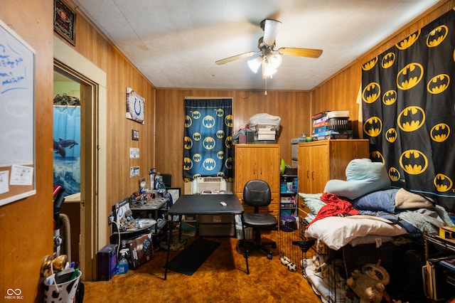 carpeted home office featuring ceiling fan and wooden walls
