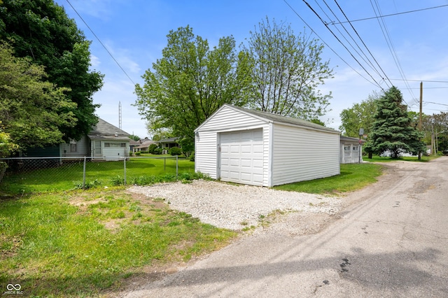 detached garage featuring fence and driveway