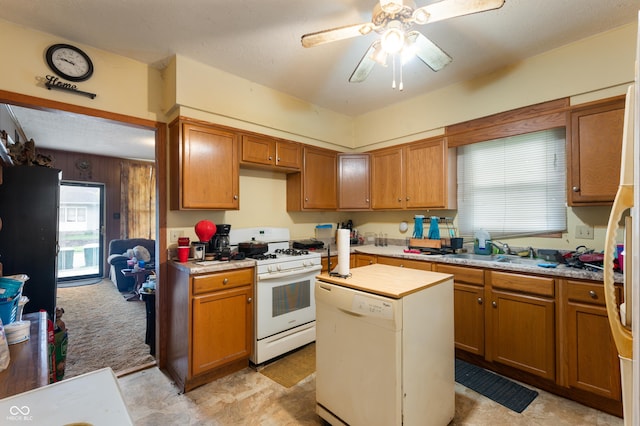 kitchen with white appliances, a sink, light countertops, and healthy amount of natural light