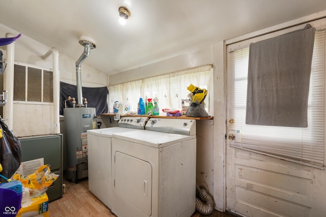 laundry room with water heater, washing machine and clothes dryer, light wood-style floors, and heating unit