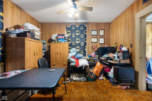 carpeted home office featuring wood walls and ceiling fan
