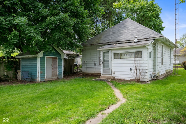 rear view of house with a shed, an outdoor structure, and a shingled roof