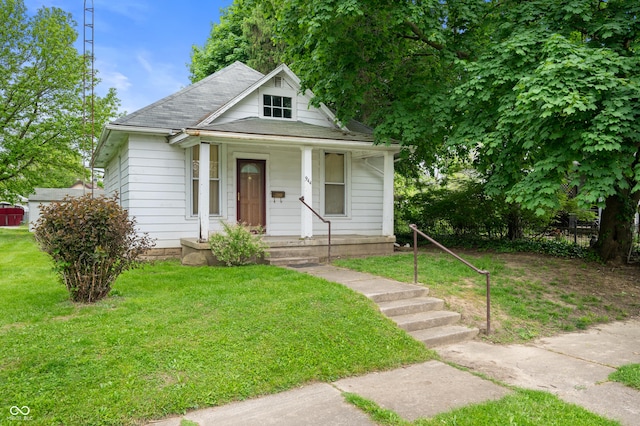 view of front of house featuring a porch, roof with shingles, and a front yard