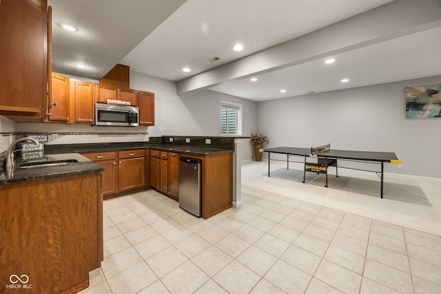 3449 Brixford Ln, West Lafayette, IN 47906 - kitchen with stainless steel microwave, a peninsula, recessed lighting, brown cabinetry, and dark stone counters