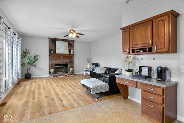 3449 Brixford Ln, West Lafayette, IN 47906 - kitchen with a ceiling fan, a brick fireplace, a textured ceiling, brown cabinetry, and backsplash