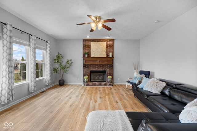 3449 Brixford Ln, West Lafayette, IN 47906 - living room with a ceiling fan, light wood finished floors, a textured ceiling, a fireplace, and baseboards