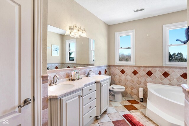 186 W 600 N, Alexandria, IN 46001 - bathroom featuring tile walls, plenty of natural light, a garden tub, wainscoting, and double vanity