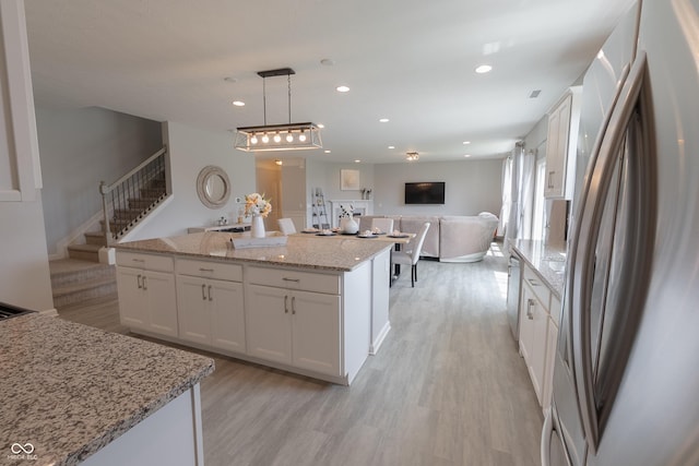 4863 Sherlock Dr, Westfield, IN 46062 - kitchen with freestanding refrigerator, light wood-style floors, white cabinetry, open floor plan, and a center island