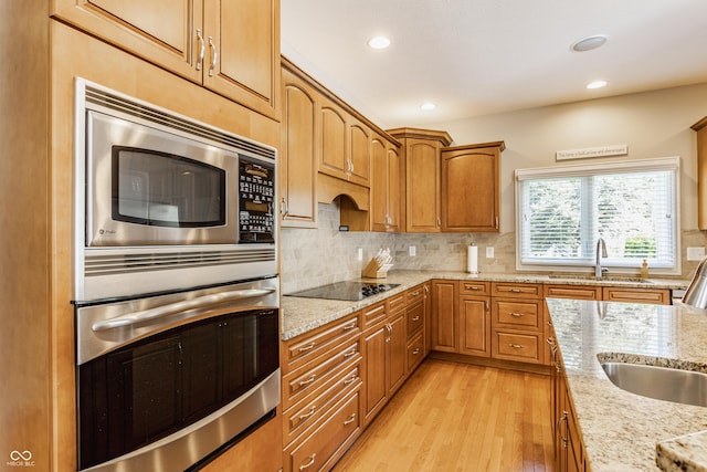 10784 Giselle Way, Fishers, IN 46040 - kitchen featuring appliances with stainless steel finishes, a sink, light wood-style flooring, light stone counters, and recessed lighting