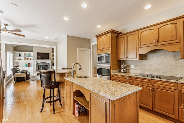10784 Giselle Way, Fishers, IN 46040 - kitchen featuring appliances with stainless steel finishes, a sink, a ceiling fan, a center island with sink, and light wood-type flooring