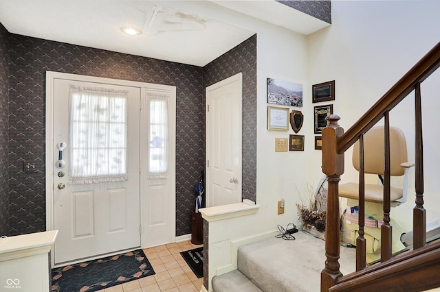 entrance foyer with stairway, light tile patterned floors, and baseboards