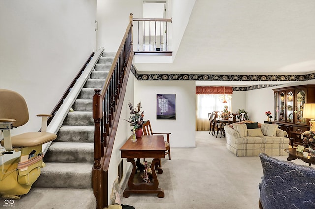 stairway with carpet flooring and a towering ceiling