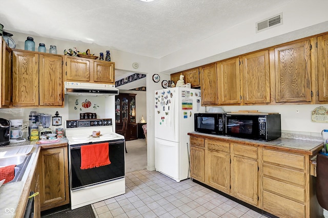 kitchen featuring white appliances, under cabinet range hood, light tile patterned floors, a textured ceiling, and brown cabinetry