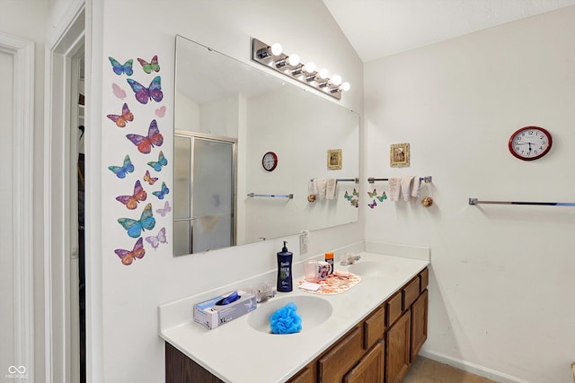 full bath with a stall shower, double vanity, and baseboards