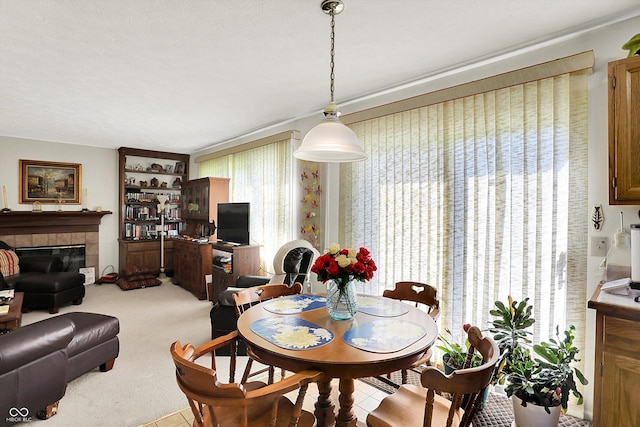 dining space with a tiled fireplace and carpet flooring
