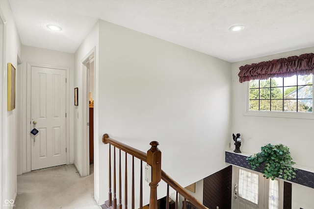 corridor with an upstairs landing, light colored carpet, and recessed lighting