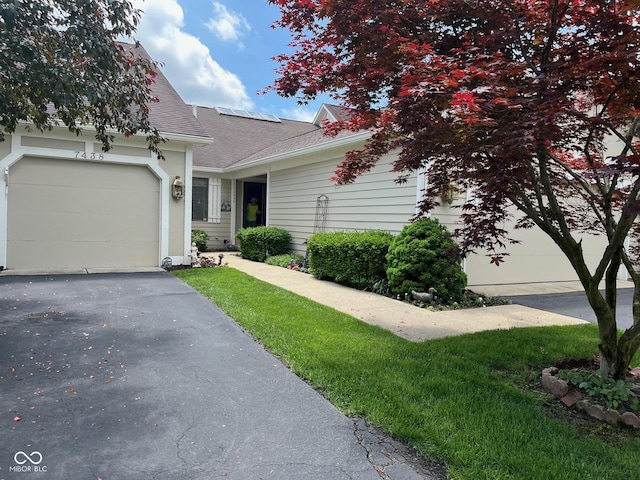 7440 Sylvan Ridge Rd, Indianapolis, IN 46240 - view of front of house with driveway, a garage, a shingled roof, and solar panels
