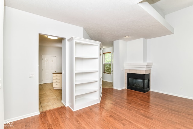 1030 Longwell Pl, Indianapolis, IN 46240 - unfurnished living room with light wood-style flooring, baseboards, a tile fireplace, and a textured ceiling