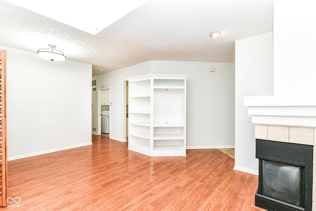 1030 Longwell Pl, Indianapolis, IN 46240 - unfurnished living room with a tiled fireplace, light wood-style floors, baseboards, and a skylight