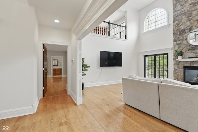 1478 W 500 S, Peru, IN 46970 - unfurnished living room featuring a stone fireplace, light wood-style flooring, baseboards, and a towering ceiling
