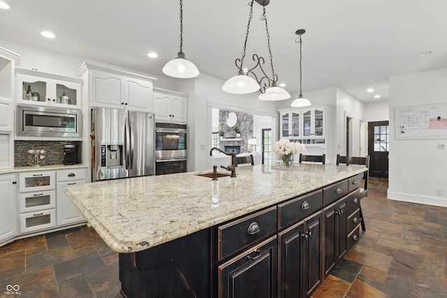 1478 W 500 S, Peru, IN 46970 - kitchen with appliances with stainless steel finishes, a sink, stone tile flooring, white cabinetry, and a center island with sink