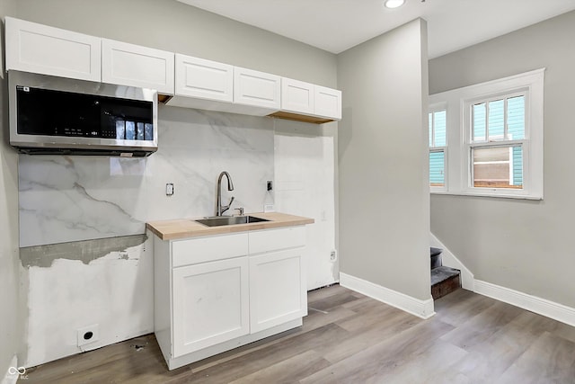 1033 N Dearborn St, Indianapolis, IN 46201 - kitchen with stainless steel microwave, a sink, white cabinets, light wood-style floors, and recessed lighting