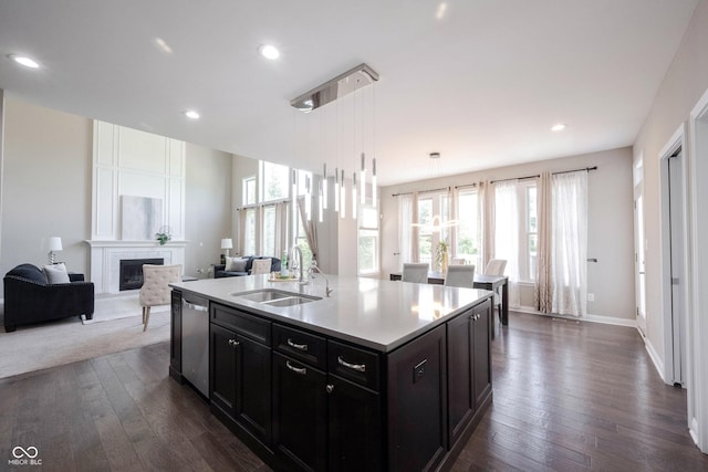 kitchen featuring a sink, dishwasher, open floor plan, dark wood-type flooring, and a fireplace
