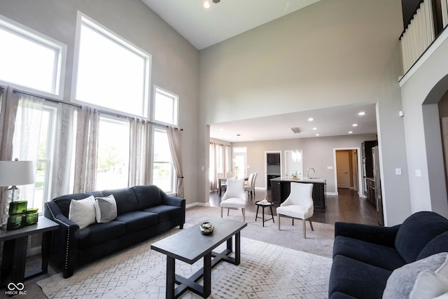 living area featuring a towering ceiling, recessed lighting, and baseboards