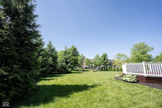 view of green lawn featuring a wooden deck