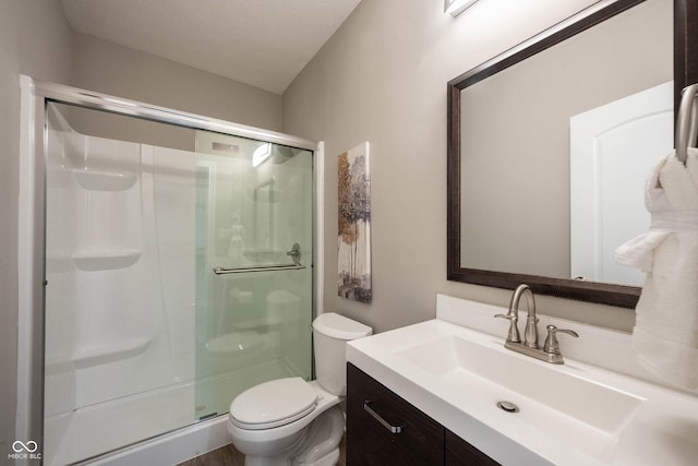 bathroom with a shower stall, toilet, and vanity