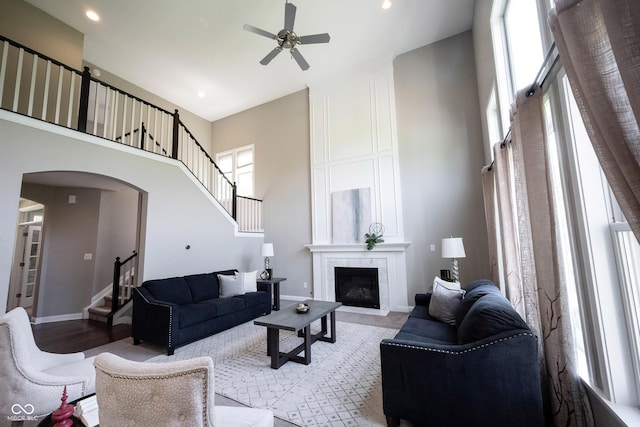 living room with stairs, a high ceiling, a ceiling fan, healthy amount of natural light, and recessed lighting