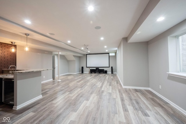 cinema with light wood-type flooring, baseboards, recessed lighting, and bar area