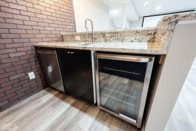 kitchen featuring wine cooler, a sink, stainless steel dishwasher, brick wall, and light wood-type flooring