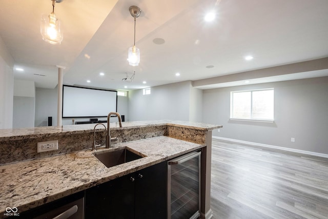 kitchen with wine cooler, a sink, recessed lighting, hanging light fixtures, and baseboards