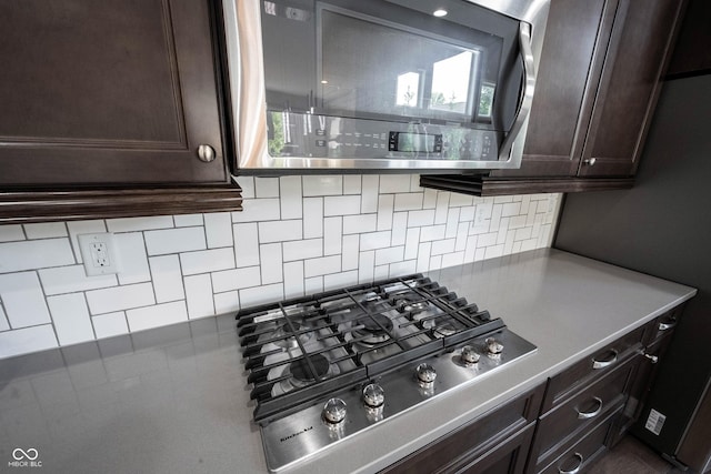 kitchen featuring stainless steel appliances, dark brown cabinets, backsplash, and light countertops