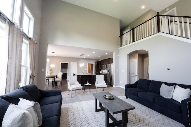 living area with a towering ceiling, arched walkways, recessed lighting, and baseboards