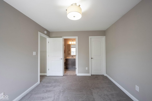 unfurnished bedroom featuring carpet floors, baseboards, and ensuite bathroom