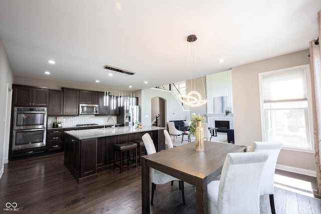 dining space with a chandelier, dark wood-type flooring, arched walkways, a fireplace, and recessed lighting